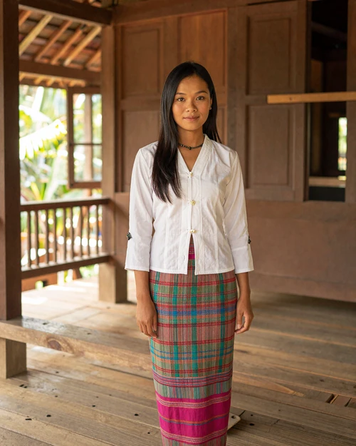 Burmese woman in traditional longyi attire inside a traditional Myanmar home