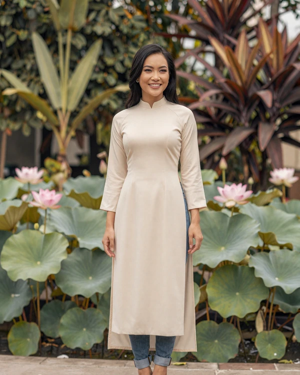 A graceful Vietnamese woman in a modern tunic standing in a traditional garden with lotus flowers