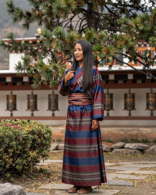 Bhutanese woman wearing traditional kira dress in a serene Himalayan garden setting