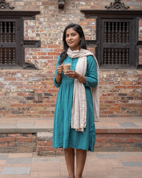 A Nepali woman enjoying chai tea in a traditional courtyard, representing everyday warmth and hospitality